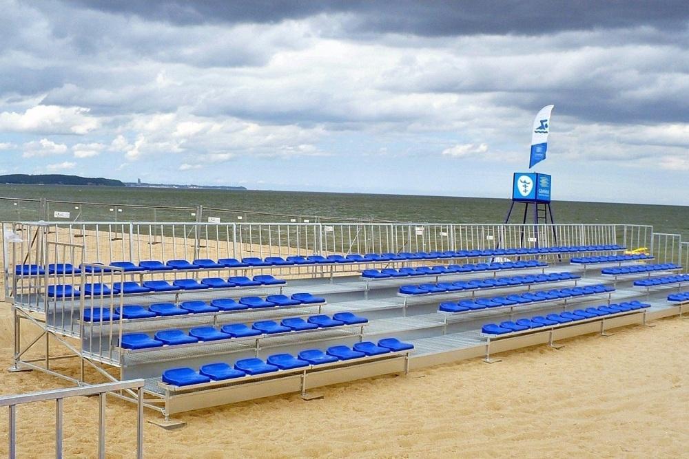 five row metal grandstands with blue strong backless stadium chairs on the beach