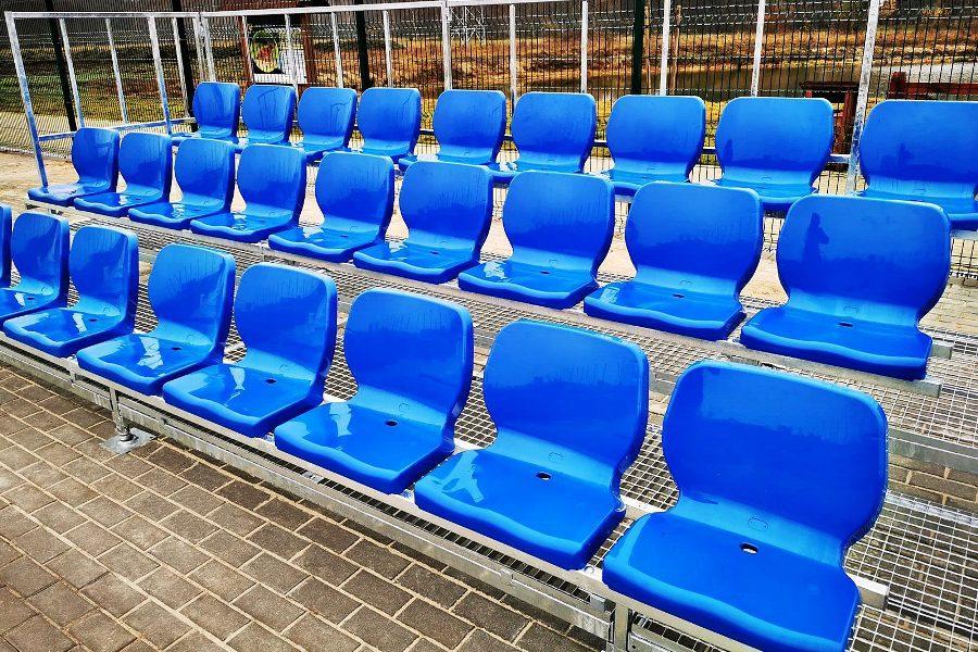 three-row bleachers with plastic blue chairs with a comfortable high back